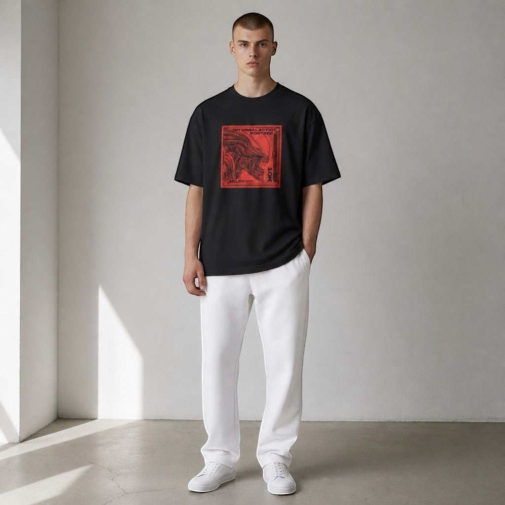A model wearing a vvicked black oversized cotton t-shirt with a red alien stamp graphic on the chest.